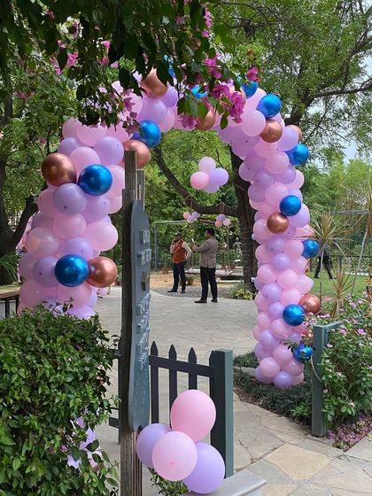 A balloon arch at the entrance of a garden party, welcoming guests to the celebration.
