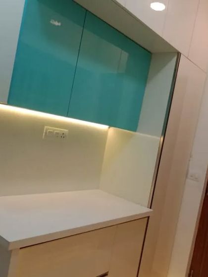 This angle shows the contrast between the vibrant teal upper cabinets and the subtle off-white lower units. This dual-tone approach creates visual interest and helps define the different functional zones within the kitchen, all while providing ample storage.