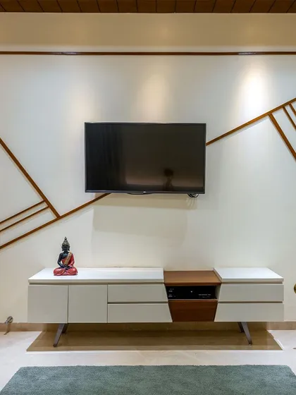 The TV unit in this living room features abstract wooden inlays on the wall, creating a piece of art that also serves a practical purpose.