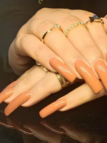 A side view of the long, caramel-nude nail extensions.