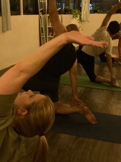 A side view of our students in a flowing sequence, moving with intention and breath. The group energy helps everyone stay motivated.