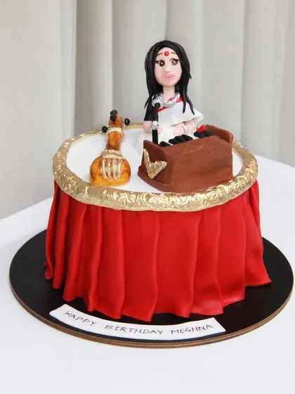 A stage for a singer. This cake was designed for a mother who is a classical singer, featuring a miniature tanpura, a harmonium, and a figurine of her, all edible.