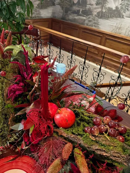 A detailed shot of the table runner, showing how fruits like pomegranates and grapes are woven into the moss and floral design.