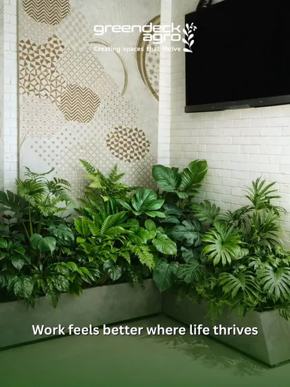A custom planter filled with a dense mix of ferns, philodendrons, and other foliage plants brings life to this waiting area. The green textures provide a natural contrast to the modern wall tiles and brick.