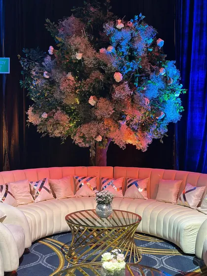 A cozy luxe corner for guests to relax in style. We designed this space with soft, curved seating, metallic accents, and a dreamy, illuminated floral tree as a backdrop. ✨🌸