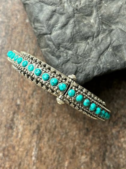 A stunning silver turquoise kada. This cuff-style bracelet is lined with beautiful turquoise stones, perfect for a bohemian look.
