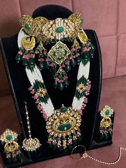 The full view of the white and green beaded bridal set, including the matching maang tikka, earrings, and nath.