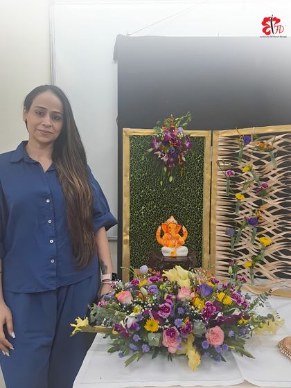One of our happy students with her finished Ganpati floral decoration. The design features a lush green backdrop, intricate woven details, and a vibrant mix of fresh flowers, all taught within our hands-on workshop.