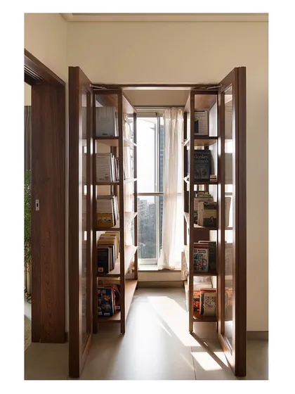 Even small spaces can have a grand purpose. We transformed a simple passage in a Mumbai apartment into a tranquil library, using custom wooden shelving and glass doors to create a quiet, sunlit nook for reading and reflection.
