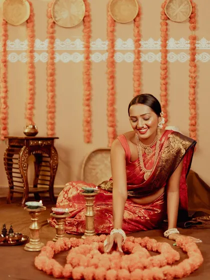 A candid moment of the model arranging a flower rangoli. These natural, interactive shots are full of life.