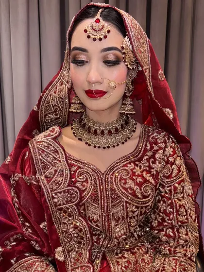 A close-up on the details of this Pakistani bridal look. The focus is on shimmery, well-defined eyes and a bold red lip that perfectly complements the intricate outfit.