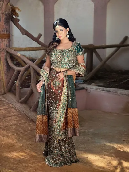A full-length shot of the model in a stunning, heavily embroidered Anarkali-style lehenga.