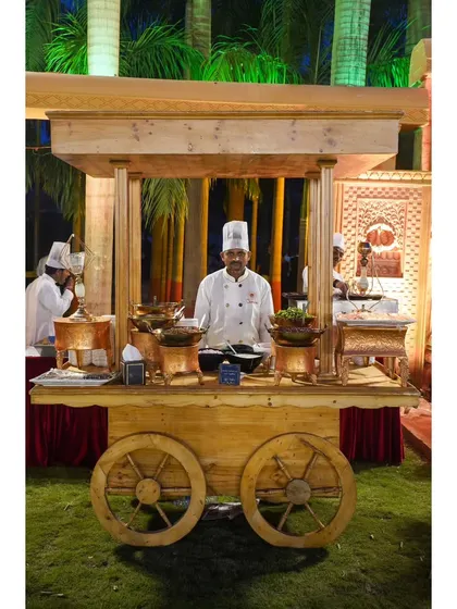 One of my chefs manning a rustic wooden chaat cart. I design themed stations like this to enhance the authenticity and visual appeal of the food.