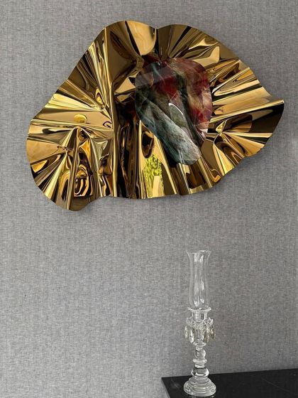 The golden sculpture's radial folds create a sunburst effect, adding warmth and luxury to the bar area.