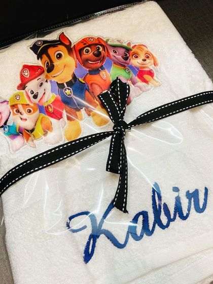 A personalised Paw Patrol themed towel, all wrapped up and ready to be gifted. It's a practical and fun present for any little fan.