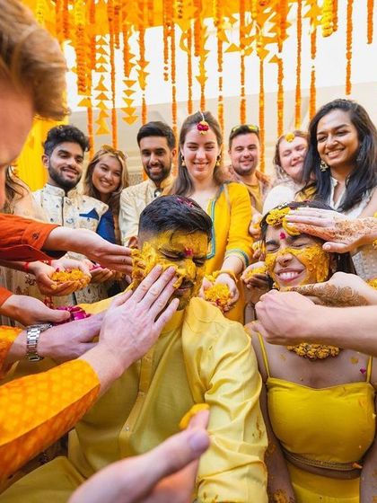 A candid moment from a Haldi ceremony, with the decor providing a perfect backdrop. The space is filled with strings of yellow and orange marigolds, reflecting the joy of the celebration.