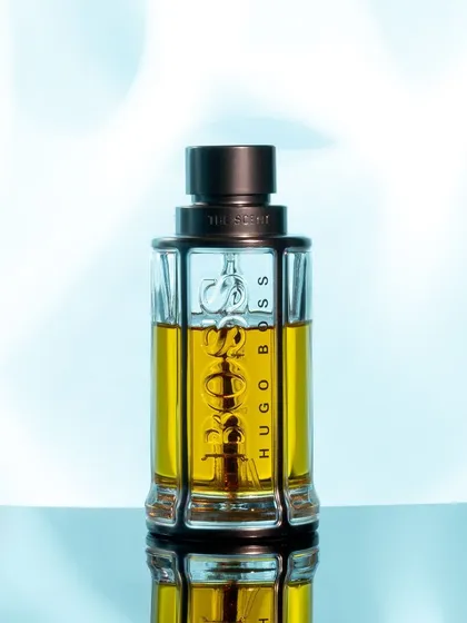 This is a clean and fresh take on a standard product shot. The cool blue, soft-focus background gives a sense of freshness, while the sharp focus on the bottle and its reflection maintains a professional, high-quality feel suitable for websites and digital ads.