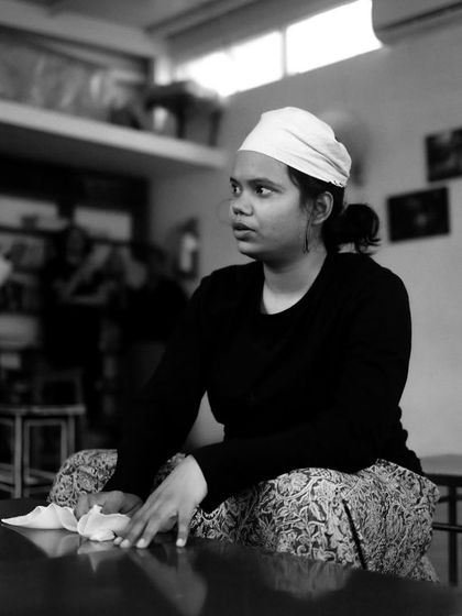 An actor cleans a table, fully in character during a rehearsal scene.