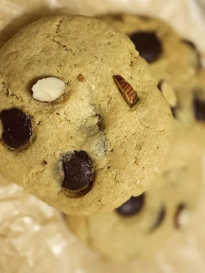 A close-up of our classic chocolate chip cookie, showing the beautiful texture and chunks of chocolate and almond.