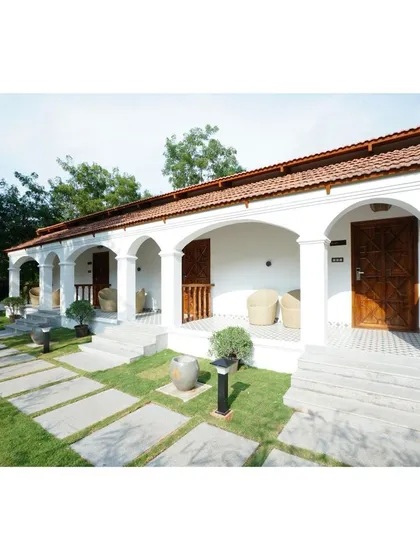 A look at a residence I designed with classic architectural elements. The clean white facade, elegant arches, and terracotta-tiled roof create a timeless and serene atmosphere, complemented by structured pathways and manicured lawns.