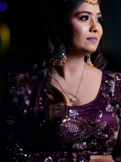 A stunning portrait of a woman in an ornate purple lehenga at her engagement event, showcasing our skill in lighting and capturing detail.