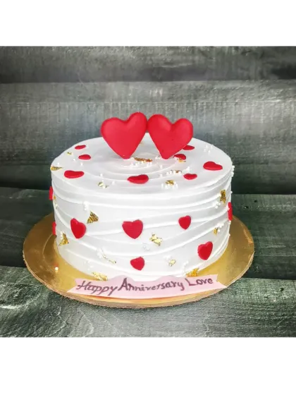 A simple yet beautiful chocolate truffle cake for an anniversary. The rustic finish is decorated with gold leaf and fondant hearts.