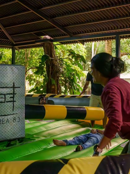 A group watches as their friends tackle the Meltdown inflatable game. The spectators have as much fun as the players.