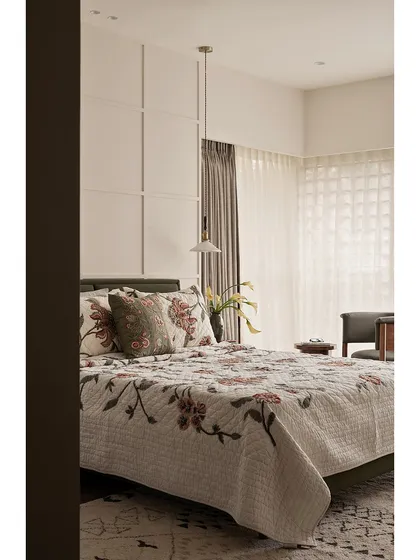 This guest bedroom from "Apartment 222" combines rest and reflection. The floral bedspread adds a touch of traditional charm, while the clean lines of the wall paneling and bedside table keep the space feeling modern and uncluttered.