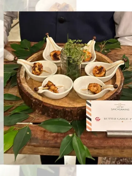 Succulent Butter Garlic Prawns, individually served in elegant tasting spoons and garnished with fresh greens. A luxurious and flavorful bite for any sophisticated gathering.