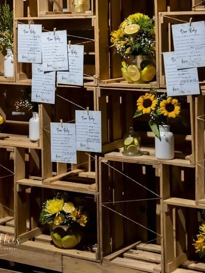A creative seating chart made from wooden crates, with guest names and table numbers clipped to strings. The crates were decorated with lemons and sunflowers to match the theme.