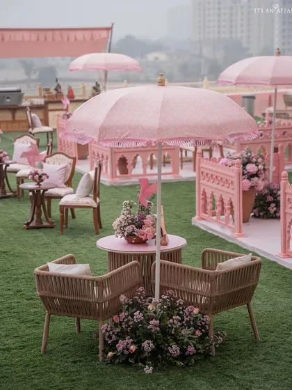A mix of modern cane chairs and traditional seating under a pink patterned umbrella, showcasing our blend of contemporary and classic styles.