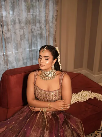 A complete look at this stunning bridal Mehendi style. The rich, multi-toned lehenga was paired with a glamorous makeup look featuring a shimmery eye, glowing skin, and a beautiful long ponytail adorned with mogra flowers.