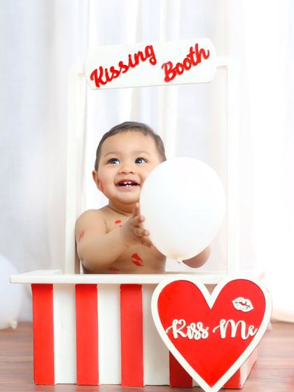 This little one is all smiles in the kissing booth, covered in lipstick marks. It's a funny and heartwarming shot that shows off his cheerful personality.