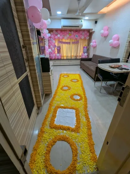 An entrance view of the welcome home decor, showing the intricate floral runner designed to welcome the baby's first steps into the home. The path leads towards the main decoration area.
