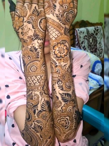A lovely shot of a client showing off her full-coverage henna. The design features flowing vines and floral elements that wrap around the hands and arms beautifully.