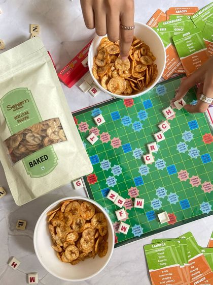 My Masaledaar Banana Chips are the perfect board game bestie. This image shows a game of Scrabble in progress, with bowls of my baked chips ready for snacking.