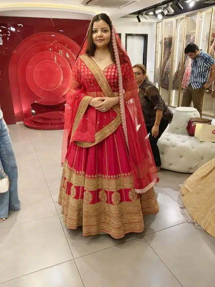 This happy client is glowing in a classic red and gold bridal lehenga. The traditional design with a broad embroidered border makes it a timeless choice for any bride.