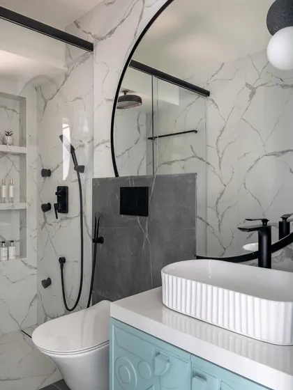 The bathroom for this kids' room features a playful mix of marble, a light blue vanity, and a unique curved mirror. The design is both stylish and child-friendly, with plenty of storage and easy-to-use fixtures.
