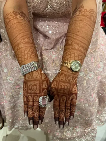 The beautiful, developed stain of an engagement mehndi, featuring the couple's initials and interlocking rings, complemented by the bride's jewelry.