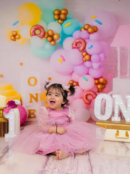 The pure, uncontainable joy of turning one. This little princess is surrounded by a pastel wonderland of donuts and ice cream props.