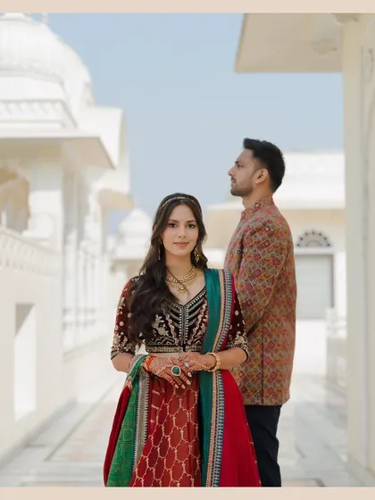 A regal portrait in a sunlit corridor. The rich colors of the bride's outfit contrast beautifully with the white walls, creating a striking and elegant pre-wedding photograph.