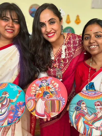 Our team dressed in traditional sarees, holding the set of three Pujo-themed wall plates.