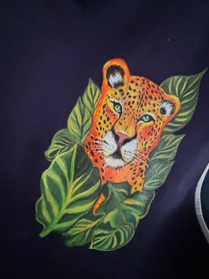 Another angle of the leopard design, showing how it wraps around the shoulder area of the jacket. The surrounding tropical leaves frame the animal and add to the wild, natural theme.