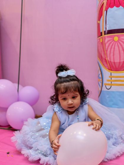 Little Shrinika playing with a balloon at her party. We use colorful props and the event's decor to create a vibrant and playful atmosphere in our photographs.