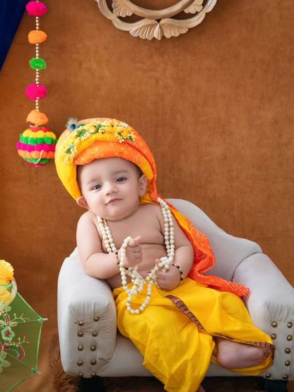 A regal pose from our little Krishna, looking thoughtful and sweet in his yellow dhoti and ornate turban.