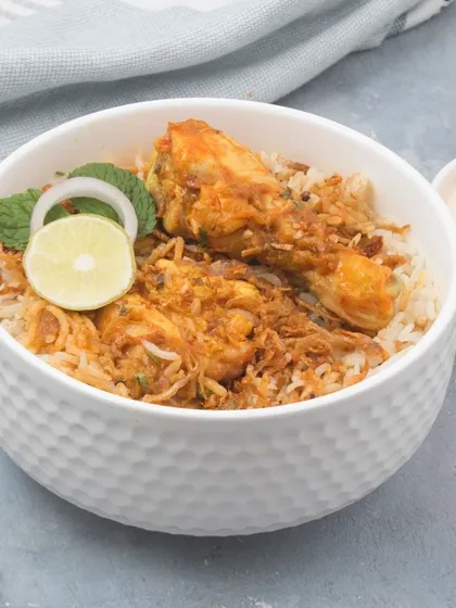 A classic bowl of our chicken dum biryani, made with fragrant long-grain rice and tender chicken pieces. We serve it with a side of cooling raita to balance the authentic spices.