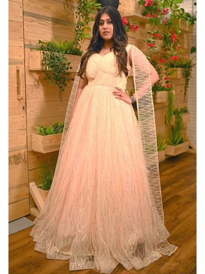 This peach gown with a sparkling overlay and attached cape sleeves is a glamorous option for any formal event, from a cocktail party to a wedding reception.