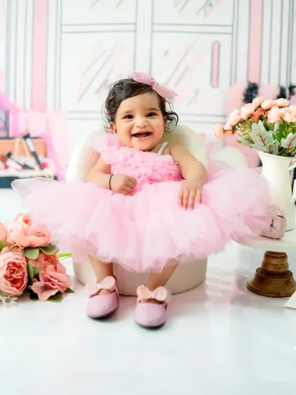 Celebrating a half-birthday in style! This 6-month-old is all smiles in her pink tutu, surrounded by flowers and a '1/2' sign in the Barbie-themed studio set.