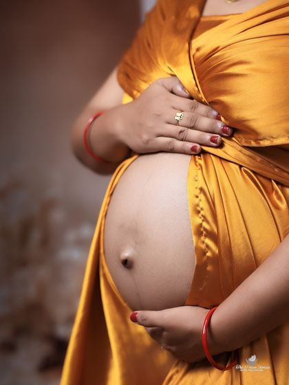 A classic bare-bump shot. This close-up focuses on the beauty of the pregnant form, with the mom's hands gently holding her belly.