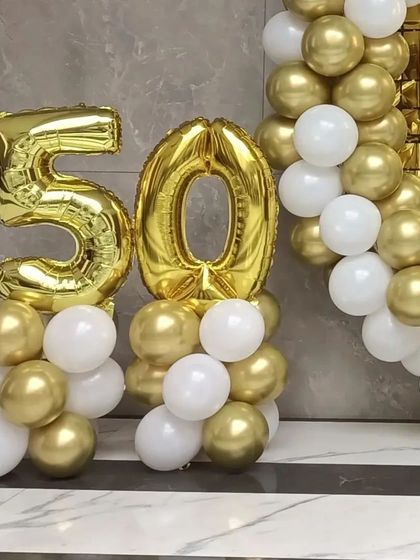 A close-up of the number '50' foil balloons on balloon pillars.
